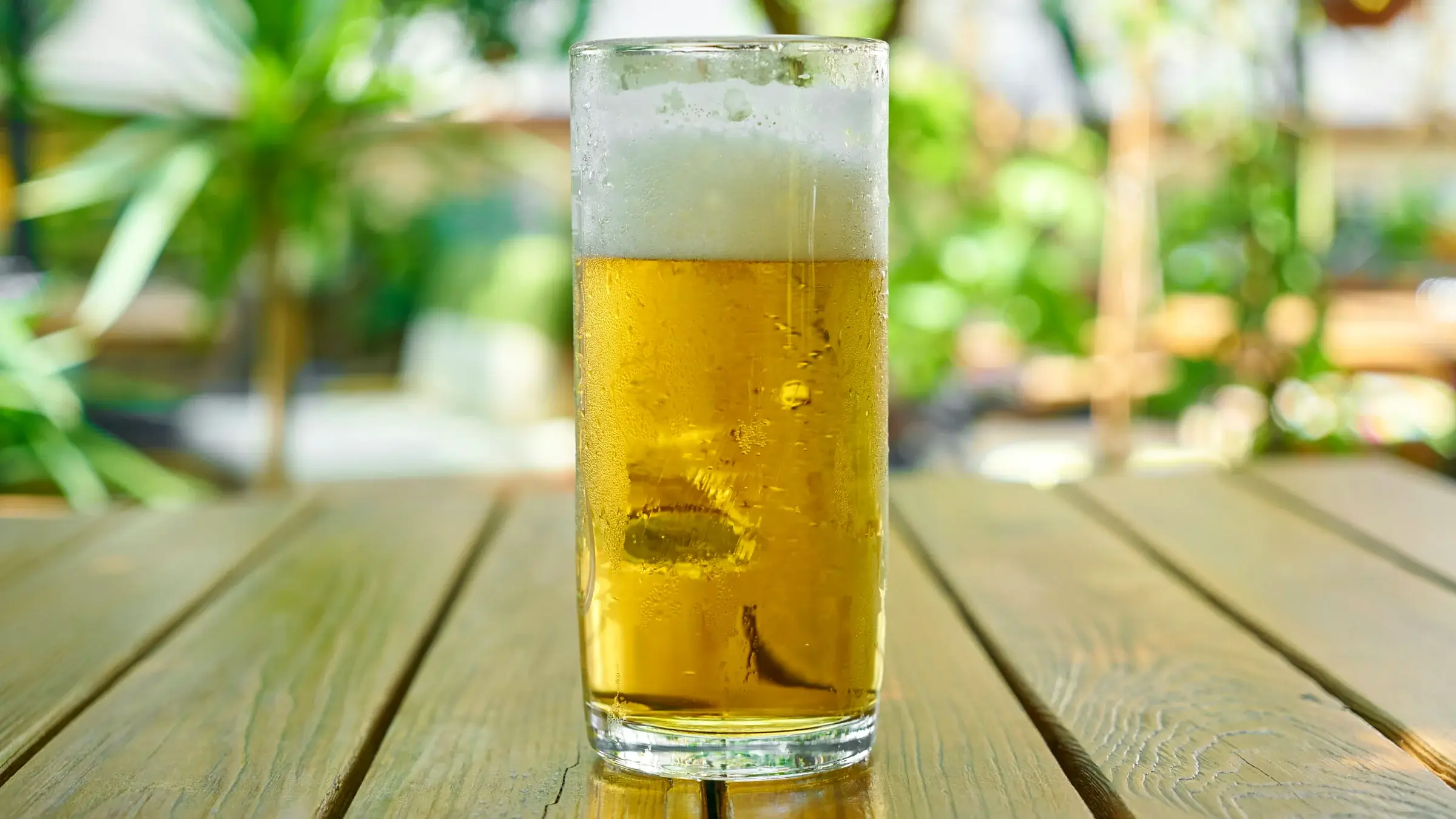 Glass of cold golden beer on a wooden table, illustrating Molly Tea's low-alcohol beer tea collaboration with Budweiser